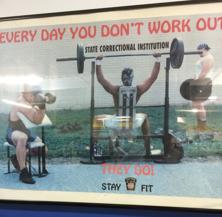 A poster that shows prison inmates lifting weights in the yard. It says "every day you don't work out, they do!"